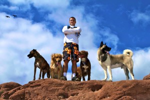 Colin West and his dog pack standing on a rock at the top of a hike.